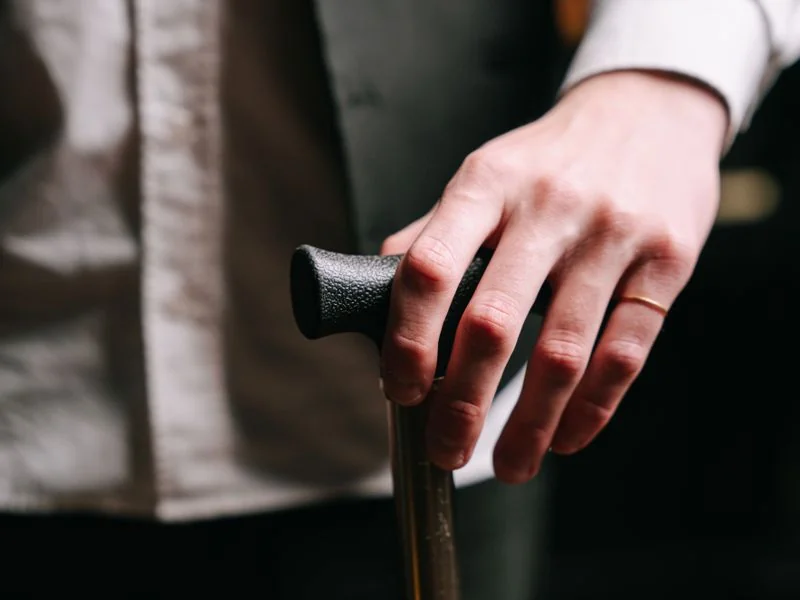 personne âgée souriante portant un bracelet téléassistance discret au poignet, assise dans son salon