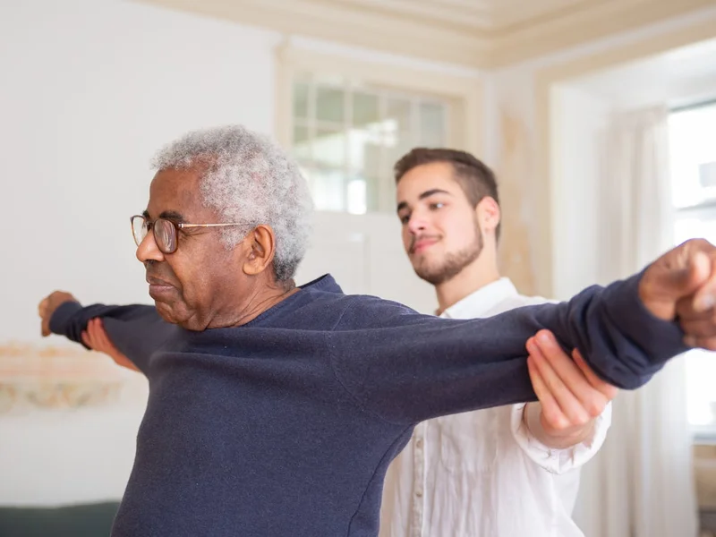 Senior aidé par son accompagnant pour des exercices doux — aide à domicile
