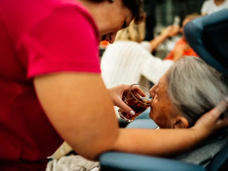 Aidante aidant une personne âgée à prendre son thé — services à domicile