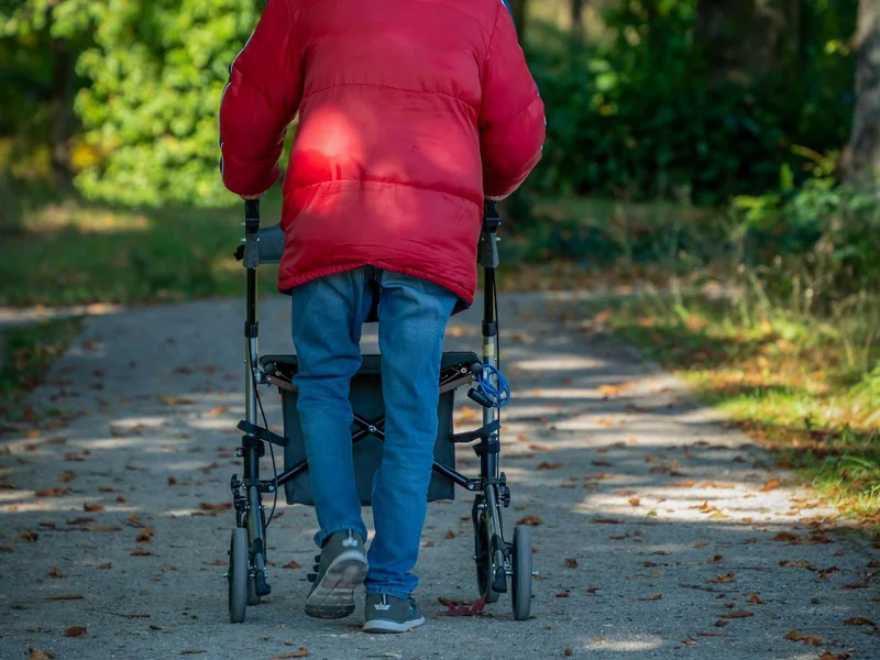 Senior avec rollator en veste rouge à l&rsquo;extérieur — mobilité quotidienne