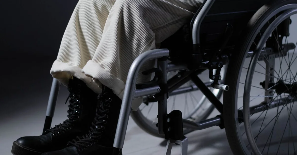 Personne en fauteuil roulant dans un couloir adapté avec rampe d'accès, intérieur lumineux
