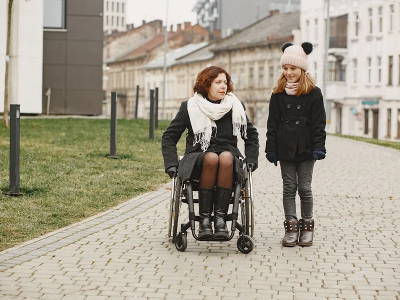 Femme en fauteuil roulant sur un chemin pavé — accessibilité et autonomie
