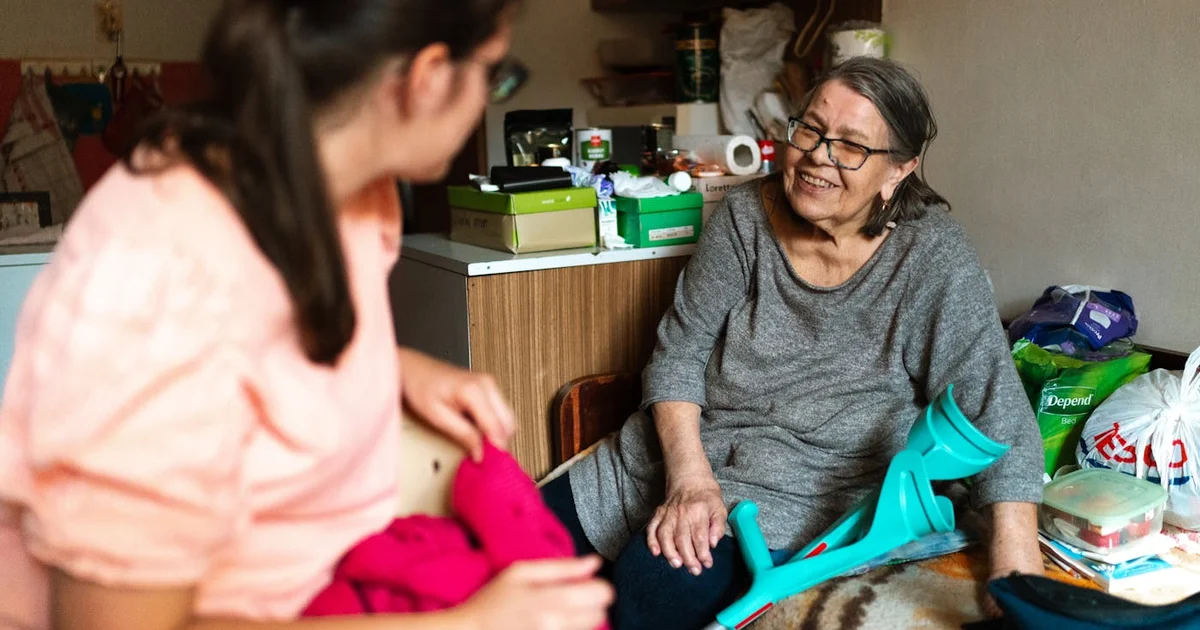 Proche aidante tenant la main d'un parent âgé dans un couloir d'hôpital, lumière douce et rassurante