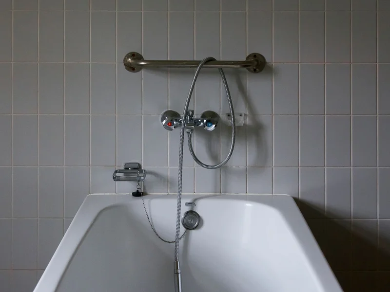 schéma technique vue de profil d&rsquo;une installation de siège de douche mural, flèches indiquant la hau