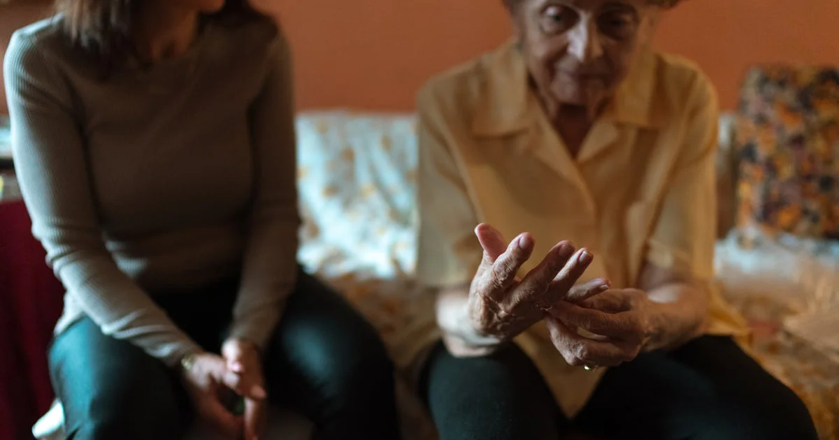 Senior appuyant sur un médaillon d'alerte rouge, en sécurité à domicile grâce à la téléassistance